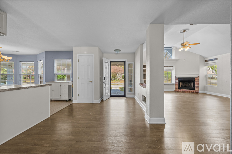 A spacious living room with a fireplace and a ceiling fan.