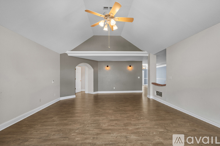 A spacious room with a ceiling fan and wooden flooring.