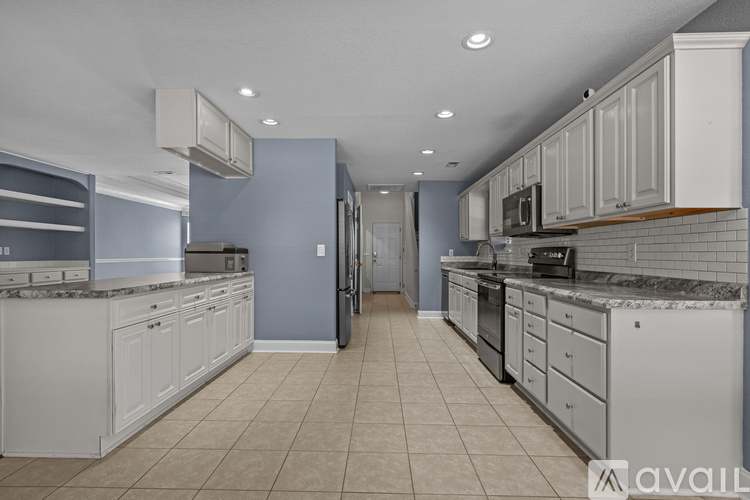 A kitchen with white cabinets and a tiled floor.