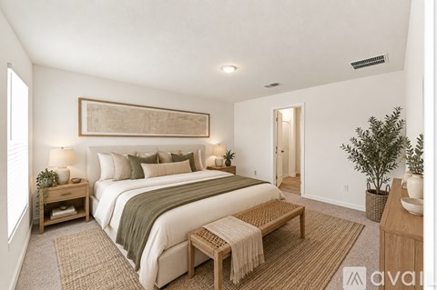 A well-lit bedroom with a large bed and a bench.