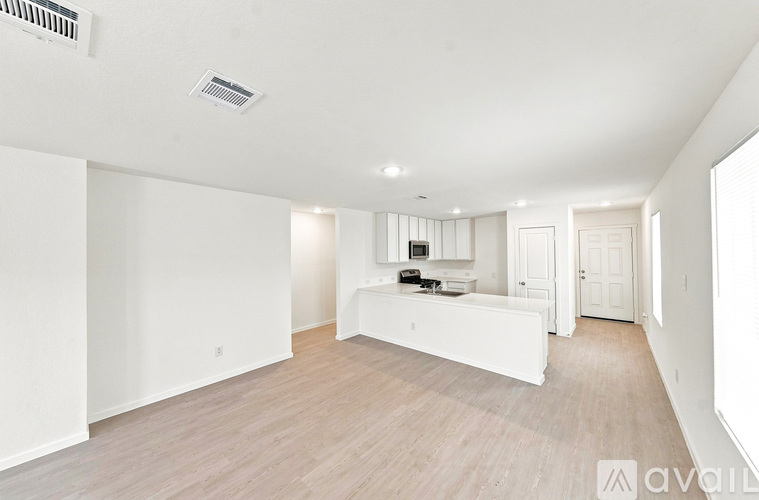 A spacious living room with a white sofa and wooden flooring.