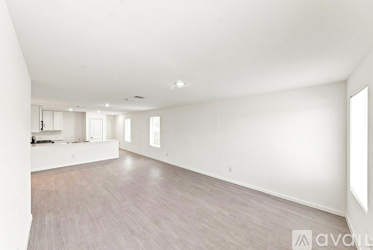 A spacious room with wooden flooring and white walls.