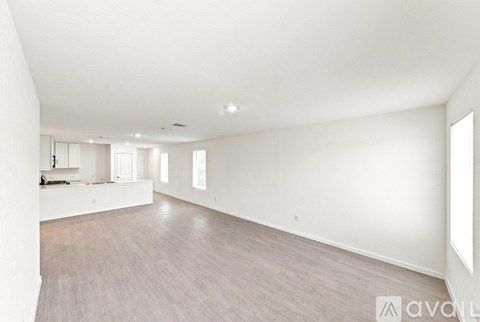 A spacious room with wooden flooring and white walls.