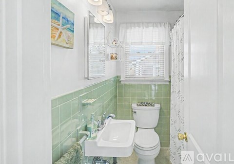 A bathroom with a green tiled wall and a white toilet.