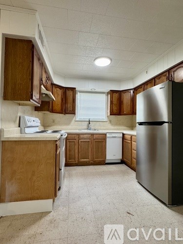 A kitchen with wooden cabinets and a stainless steel refrigerator.