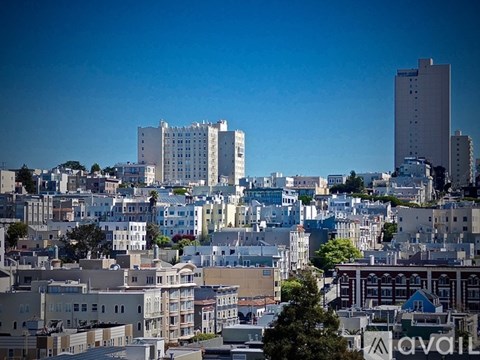A cityscape with buildings of various heights and architectural styles under a clear blue sky.