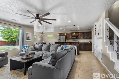 A living room with a grey couch and a ceiling fan.