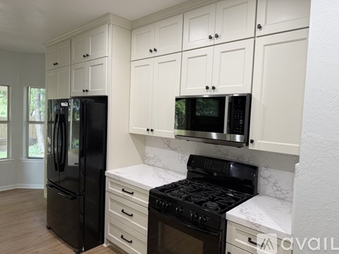 A kitchen with white cabinets and black appliances.