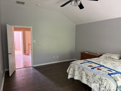 A bedroom with a bed, dresser, and a ceiling fan.