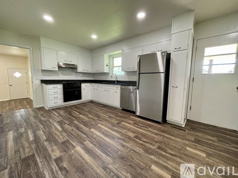 A kitchen with wood flooring and white cabinets.