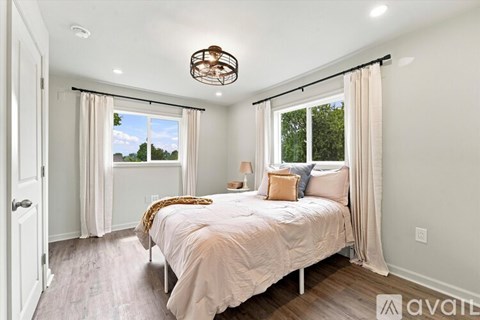 A bedroom with a large bed and a window with curtains.