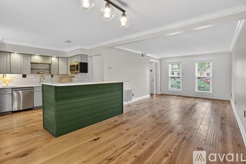 A kitchen with a green island and wooden floors.