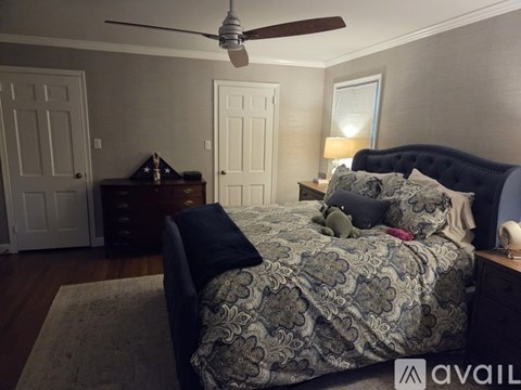 A bedroom with a bed, dresser, and ceiling fan.
