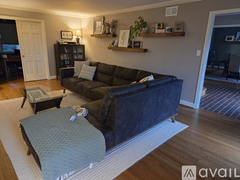 A living room with a dark sofa and a grey ottoman.