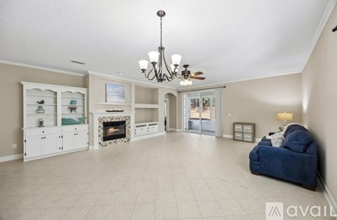 A spacious living room with a fireplace and a chandelier.