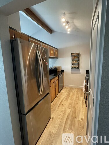 A kitchen with a stainless steel refrigerator and wooden floors.