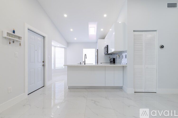 A kitchen with white cabinets and a marble floor.