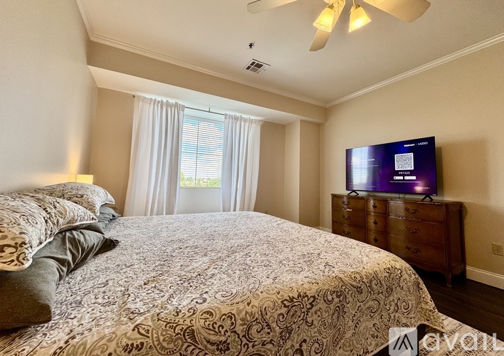 A bedroom with a large bed and a television on a dresser.