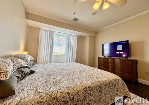 A bedroom with a large bed and a television on a dresser.