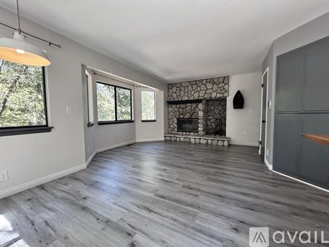 A spacious room with a fireplace and wood flooring.