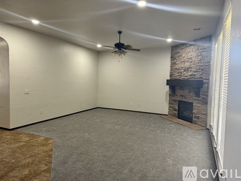 A spacious room with a fireplace and a ceiling fan.