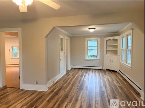 A spacious room with wooden floors and white walls.