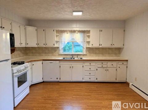 A kitchen with white cabinets and a wooden floor.