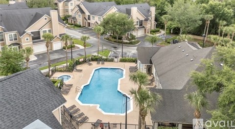 A bird's eye view of a residential area with houses, a swimming pool, and palm trees.