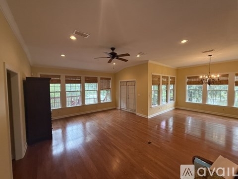 A spacious room with wood flooring and a ceiling fan.