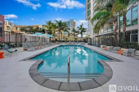 A large outdoor swimming pool surrounded by palm trees and lounge chairs.