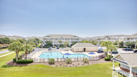 A large swimming pool surrounded by a fence and a grassy area with a few trees.
