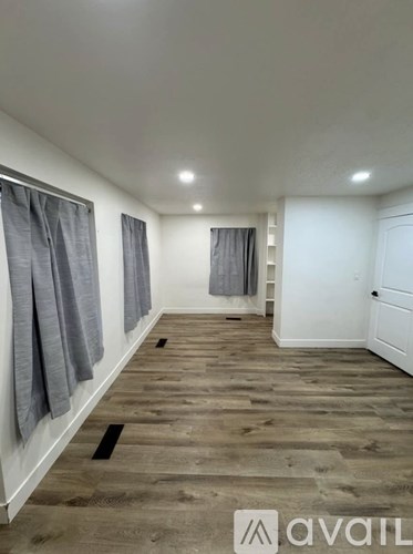 A room with wooden flooring and white walls.