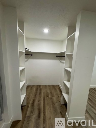 A white closet with shelves and a wooden floor.