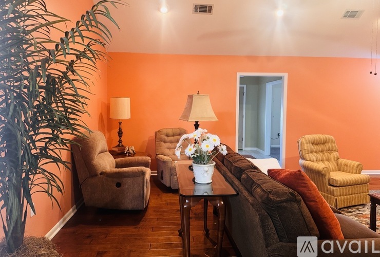 A living room with orange walls and a variety of seating options.