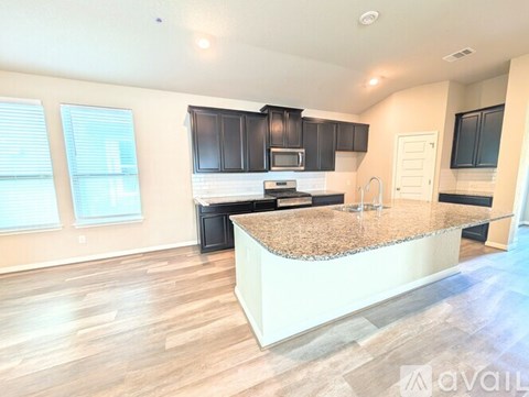 A kitchen with a granite countertop and black cabinets.