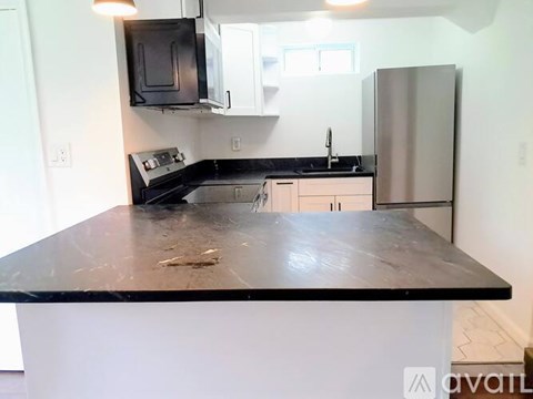 A kitchen with a black countertop and stainless steel appliances.