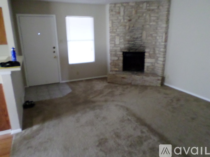 A room with a stone fireplace and a carpeted floor.