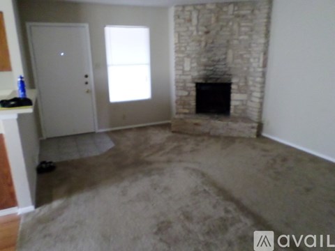 A room with a stone fireplace and a carpeted floor.