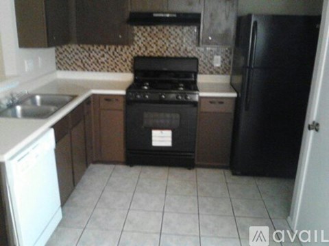 A kitchen with a black refrigerator, white sink, and a black stove top oven.