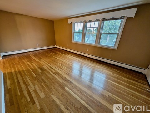 A room with wooden flooring and a window with a view of trees.