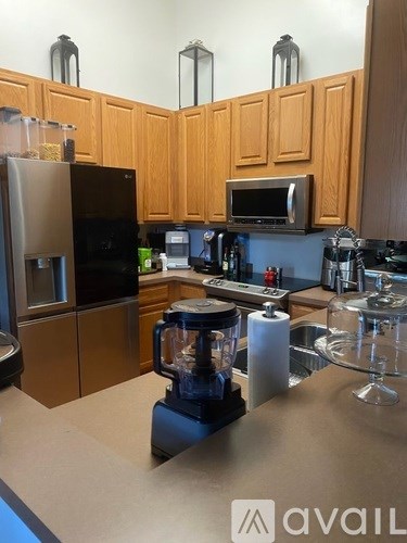 A kitchen with wooden cabinets and a black fridge.