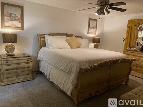 A bedroom with a large bed, a dresser, and a ceiling fan.