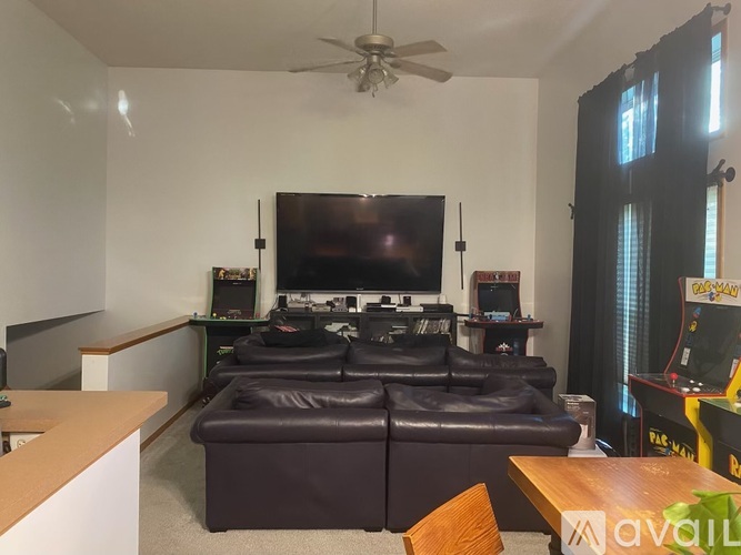 A living room with a brown leather couch and a flat screen TV mounted on the wall.