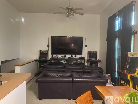 A living room with a brown leather couch and a flat screen TV mounted on the wall.