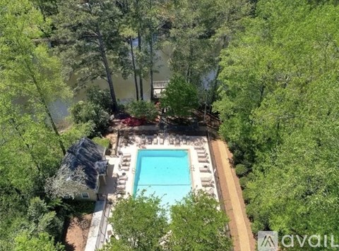 A pool surrounded by trees and a patio area.