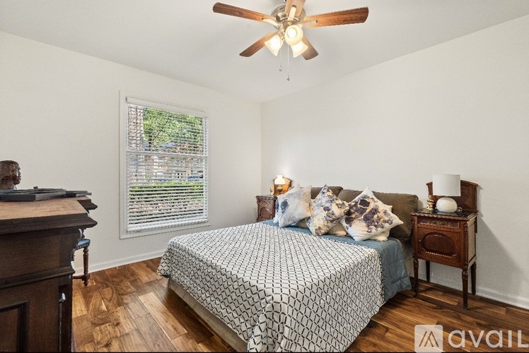 A bedroom with a bed, nightstand, and window with blinds.