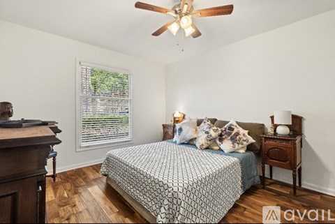 A bedroom with a bed, nightstand, and window with blinds.