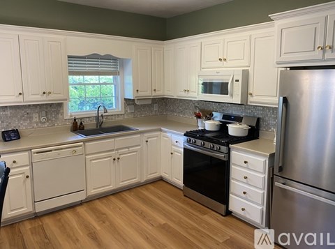 A kitchen with white cabinets and a wooden floor.