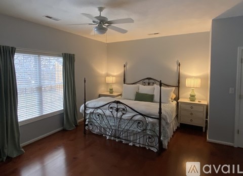 A bedroom with a bed, nightstand, and window.