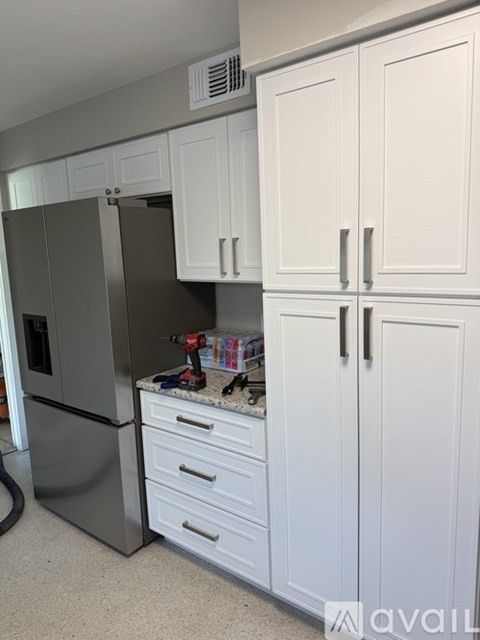 A kitchen with white cabinets and a stainless steel refrigerator.